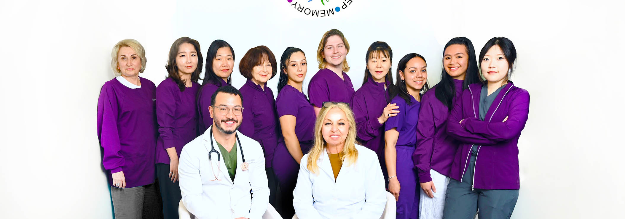 The image shows a group of individuals wearing scrubs, posing together for a photograph with a white background.
