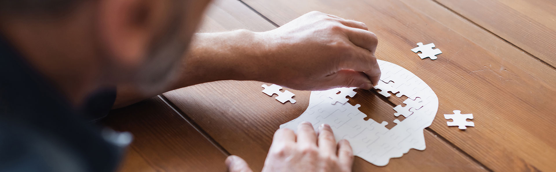 The image shows two hands working together to place puzzle pieces into their respective slots, suggesting an activity focused on problem-solving or assembly.
